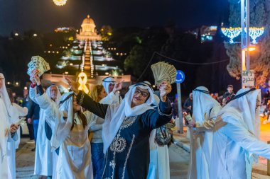 Hayfa, İsrail - 31 Aralık 2025: Katar Şeyhi gibi giyinmiş bir grup aktivist, Katar-kapısı yolsuzluk olayının sembolik bir protestosu olarak insanlara para dağıtıyor. Alman Kolonisi, Hayfa, İsrail