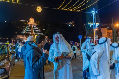Hayfa, İsrail - 31 Aralık 2025: Katar Şeyhi gibi giyinmiş bir grup aktivist, Katar-kapısı yolsuzluk olayının sembolik bir protestosu olarak insanlara para dağıtıyor. Alman Kolonisi, Hayfa, İsrail