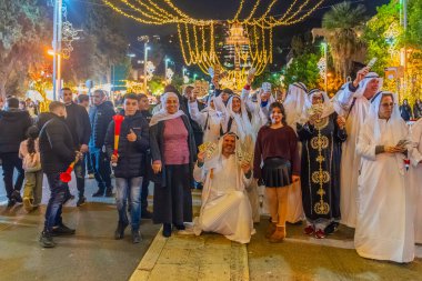 Hayfa, İsrail - 31 Aralık 2025: Katar Şeyhi gibi giyinmiş bir grup aktivist, Katar-kapısı yolsuzluk olayının sembolik bir protestosu olarak insanlara para dağıtıyor. Alman Kolonisi, Hayfa, İsrail