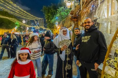 Hayfa, İsrail - 31 Aralık 2025: Katar Şeyhi gibi giyinmiş bir grup aktivist, Katar-kapısı yolsuzluk olayının sembolik bir protestosu olarak insanlara para dağıtıyor. Alman Kolonisi, Hayfa, İsrail