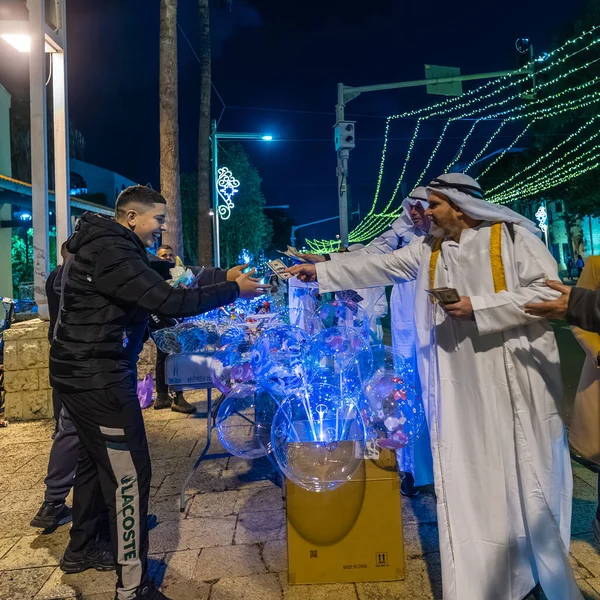 Hayfa, İsrail - 31 Aralık 2025: Katar Şeyhi gibi giyinmiş bir grup aktivist, Katar-kapısı yolsuzluk olayının sembolik bir protestosu olarak insanlara para dağıtıyor. Alman Kolonisi, Hayfa, İsrail