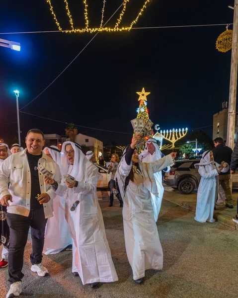 Hayfa, İsrail - 31 Aralık 2025: Katar Şeyhi gibi giyinmiş bir grup aktivist, Katar-kapısı yolsuzluk olayının sembolik bir protestosu olarak insanlara para dağıtıyor. Alman Kolonisi, Hayfa, İsrail