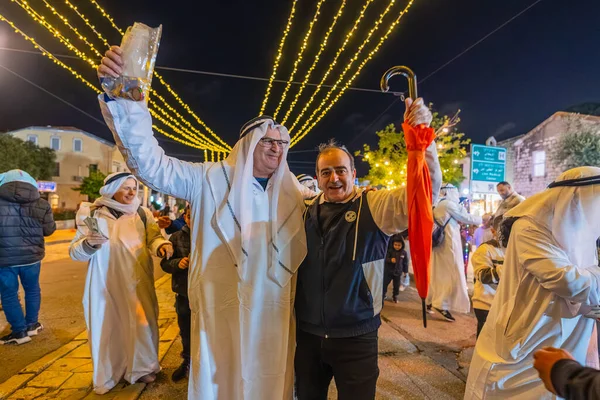 Hayfa, İsrail - 31 Aralık 2025: Katar Şeyhi gibi giyinmiş bir grup aktivist, Katar-kapısı yolsuzluk olayının sembolik bir protestosu olarak insanlara para dağıtıyor. Alman Kolonisi, Hayfa, İsrail