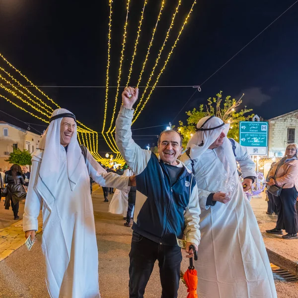 Hayfa, İsrail - 31 Aralık 2025: Katar Şeyhi gibi giyinmiş bir grup aktivist, Katar-kapısı yolsuzluk olayının sembolik bir protestosu olarak insanlara para dağıtıyor. Alman Kolonisi, Hayfa, İsrail