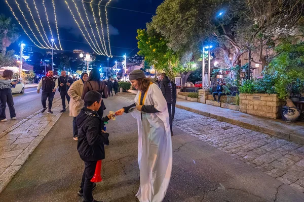 Hayfa, İsrail - 31 Aralık 2025: Katar Şeyhi gibi giyinmiş bir grup aktivist, Katar-kapısı yolsuzluk olayının sembolik bir protestosu olarak insanlara para dağıtıyor. Alman Kolonisi, Hayfa, İsrail