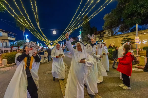 Hayfa, İsrail - 31 Aralık 2025: Katar Şeyhi gibi giyinmiş bir grup aktivist, Katar-kapısı yolsuzluk olayının sembolik bir protestosu olarak insanlara para dağıtıyor. Alman Kolonisi, Hayfa, İsrail