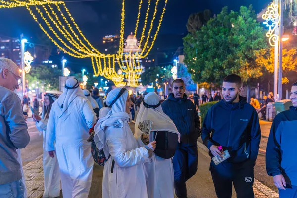 Hayfa, İsrail - 31 Aralık 2025: Katar Şeyhi gibi giyinmiş bir grup aktivist, Katar-kapısı yolsuzluk olayının sembolik bir protestosu olarak insanlara para dağıtıyor. Alman Kolonisi, Hayfa, İsrail