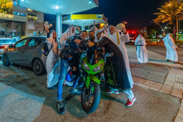 Hayfa, İsrail - 31 Aralık 2025: Katar Şeyhi gibi giyinmiş bir grup aktivist, Katar-kapısı yolsuzluk olayının sembolik bir protestosu olarak insanlara para dağıtıyor. Alman Kolonisi, Hayfa, İsrail