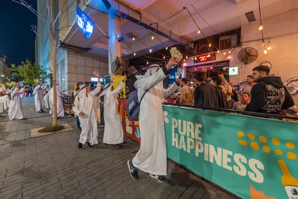 Hayfa, İsrail - 31 Aralık 2025: Katar Şeyhi gibi giyinmiş bir grup aktivist, Katar-kapısı yolsuzluk olayının sembolik bir protestosu olarak insanlara para dağıtıyor. Şehir merkezi, Hayfa, İsrail