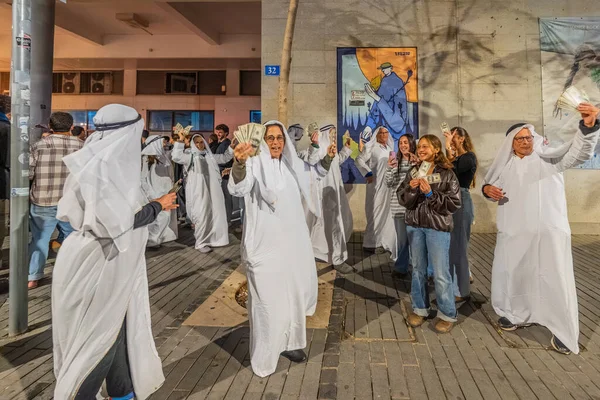 Hayfa, İsrail - 31 Aralık 2025: Katar Şeyhi gibi giyinmiş bir grup aktivist, Katar-kapısı yolsuzluk olayının sembolik bir protestosu olarak insanlara para dağıtıyor. Şehir merkezi, Hayfa, İsrail