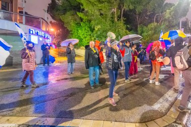 Hayfa, İsrail - 10 Ocak 2026: Çeşitli tabelaları ve bayrakları olan insanlar, hükümete karşı düzenlenen bir protesto mitingine katıldı, yeni polis gereksinimleri nedeniyle kaldırıma itildi. Hayfa, İsrail