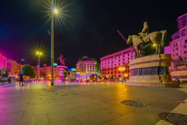 Üsküp, Kuzey Makedonya - 04 Ekim 2023: Makedonya Meydanı 'nda Üsküp, Kuzey Makedonya' da çeşitli anıtlar, yerel halk ve ziyaretçilerin yer aldığı akşam manzarası