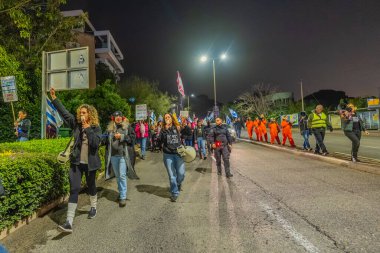 Hayfa, İsrail - 24 Ocak 2026: Çeşitli tabelaları ve bayrakları olan insanlar, hükümete karşı düzenlenen bir protesto mitingine katıldı, yeni polis gereksinimleri nedeniyle kaldırıma itildi. Hayfa, İsrail