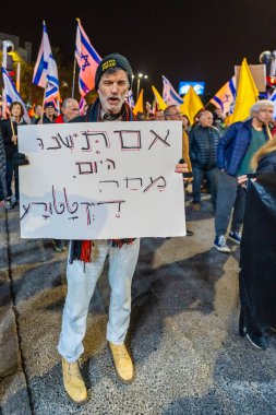 Hayfa, İsrail - 24 Ocak 2026: Çeşitli tabelaları ve bayrakları olan insanlar, hükümete karşı düzenlenen bir protesto mitingine katıldı, yeni polis gereksinimleri nedeniyle kaldırıma itildi. Hayfa, İsrail