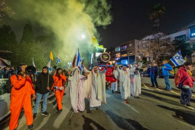 Hayfa, İsrail - 24 Ocak 2026: Katarlı Şeyh gibi giyinmiş aktivistler, Katarlı yolsuzluk olayının sembolik bir protestosu olarak bir lokomotif taşıyorlar. İsrail, Hayfa 'da düzenlenen bir protesto mitinginde.
