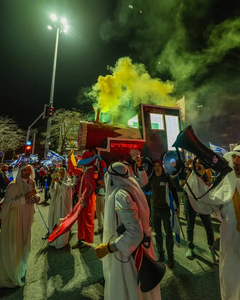 Hayfa, İsrail - 24 Ocak 2026: Katarlı Şeyh gibi giyinmiş aktivistler, Katarlı yolsuzluk olayının sembolik bir protestosu olarak bir lokomotif taşıyorlar. İsrail, Hayfa 'da düzenlenen bir protesto mitinginde.