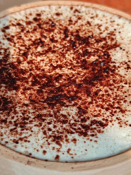 Tahta bir masada tarçınlı bir fincan kapuçino. en üstteki görünüm