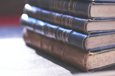 Birkaç eski ve biraz yıpranmış kitap bir masanın üstündeki kulede duruyor.