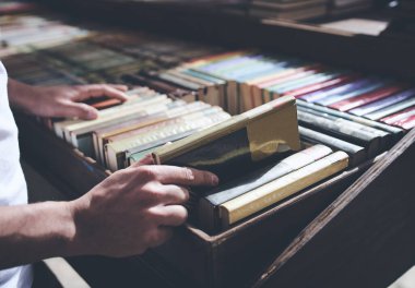 Erkek el, yatay bir ahşap kitaplıktan kitap çıkarıyor.