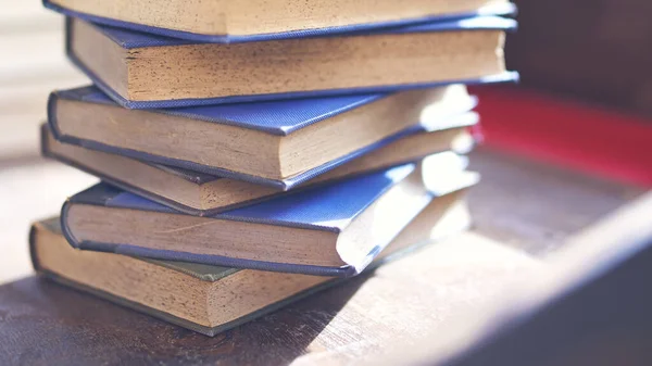 Birkaç eski ve biraz yıpranmış kitap bir masanın üstündeki kulede duruyor.