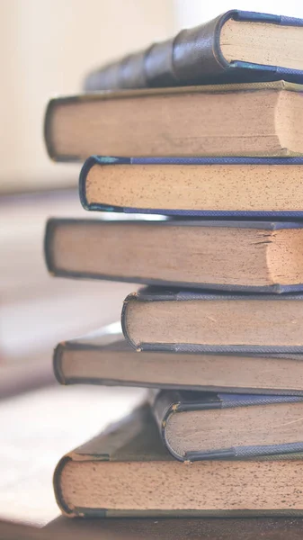 Birkaç eski ve biraz yıpranmış kitap bir masanın üstündeki kulede duruyor.