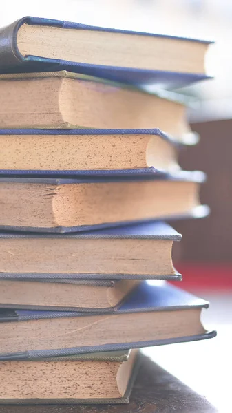 Birkaç eski ve biraz yıpranmış kitap bir masanın üstündeki kulede duruyor.