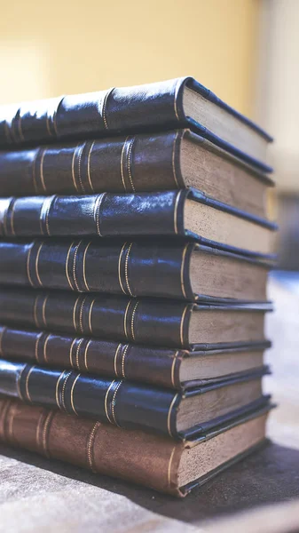 Birkaç eski ve biraz yıpranmış kitap bir masanın üstündeki kulede duruyor.