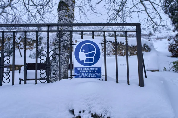 Brihuega, İspanya - 9 Ocak 2021: Bir tabela, Brihuega (İspanya) sokaklarından birinde Filomena kar fırtınasının geçmesinden sonra insanlara maskenin kullanımını hatırlatıyor. COVID