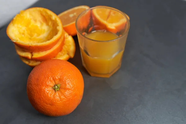 Glas Gepresster Orangensaft Und Schalen Auf Grauem Tisch — Stockfoto