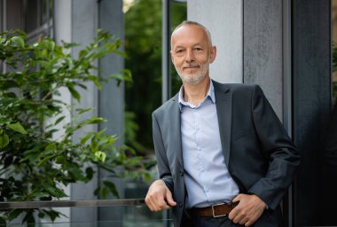 Gri takım elbiseli adam korkuluklara yaslandı..