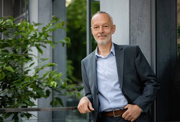 Gri takım elbiseli adam korkuluklara yaslandı..