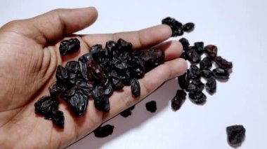 Close up of organic rainsis in hand on white background. Small black rainsis in hand.