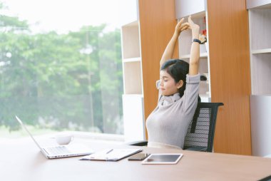 Güzel Asyalı iş kadını, dinlenme odasında ellerini uzatıyor. Yaşam tarzı kadın, konsept çalışmadan sonra rahatlar..