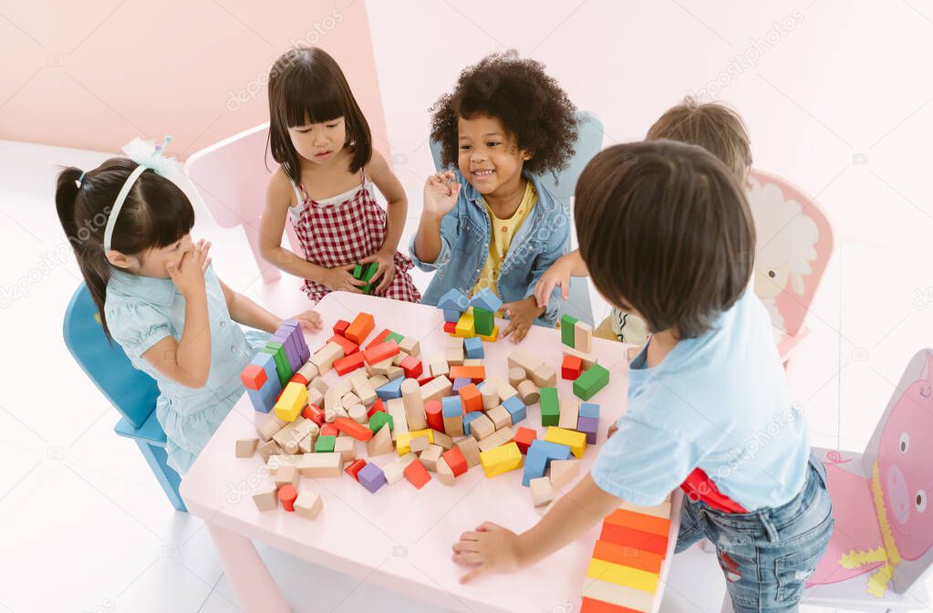 Ethnicity diversity group of kids playing with colorful blocks on table in class at the kindergarten. Kindergarten international school education concept. Top view.