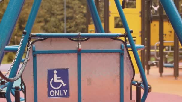 Gesperrte Schaukel für Rollstuhlfahrer auf leerem Spielplatz — Stockvideo