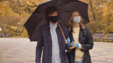 Parkta yürüyen koruyucu maskeli bir çift.