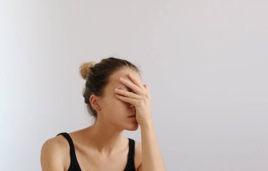 Üzgün kadın eliyle yüzünü kapatıyor. Baş ağrısı ya da stres. Beyaz arka plan, depresif ruh hali. Mükemmel vücut derisi. Boşluğu kopyala.
