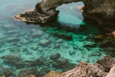 Altında berrak mavi su olan güzel kayalık bir uçurum. Yaz seyahati, deniz kıyısı.