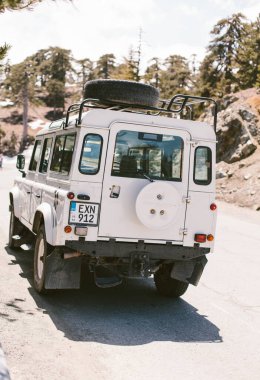 Troodos, Kıbrıs - 20.04.2019. Dağlarda beyaz bir cip var. Gezintiye çıkan cip safarisi. Seyahat maceraları. 