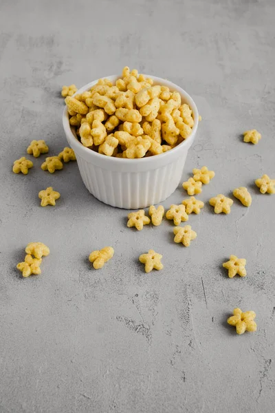 Star shaped honey coated cereal in a white bowl and wooden