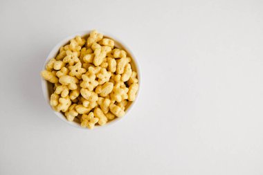 Bal Yıldızları kahvaltı gevreğini beyaz kaseye koyar. Sağlıklı tam tahıl tadı. Üst Manzara. Uzayı kopyala Çocuklar için yiyecek..