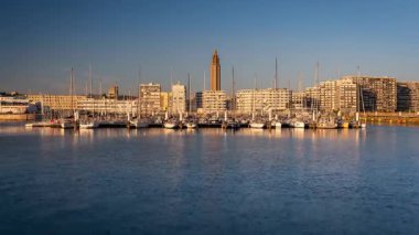 Le Havre, Fransa 'daki marina, arka planda ünlü St. Joseph Kilisesi ile altın saatinde görüldü. Zaman aşımı klibi