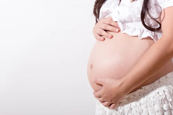 Pregnant woman caressing her belly over white background — Stock Photo, Image