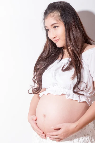 Беременная женщина ласкает живот на белом фоне — стоковое фото
