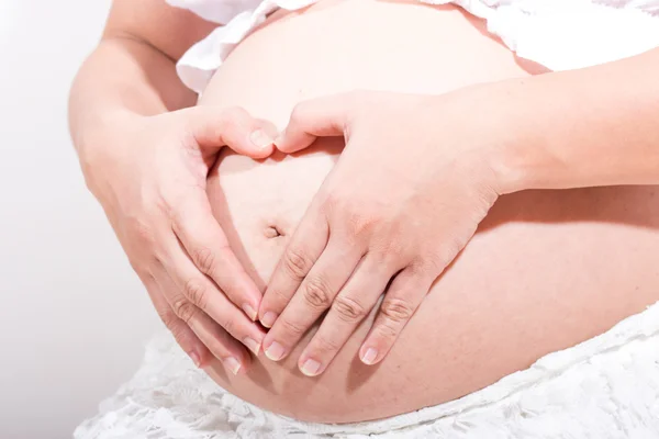 Donna incinta accarezzando la pancia su sfondo bianco — Foto Stock