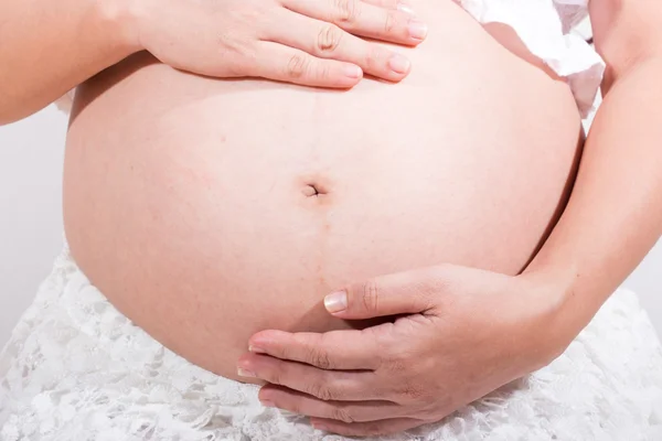 Femme enceinte caressant son ventre sur fond blanc — Photo