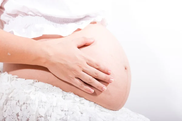 Zwanger vrouw strelen haar buik over witte achtergrond — Stockfoto