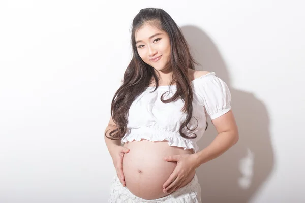Těhotná žena laskání její břicho přes bílé pozadí Royalty Free Stock Obrázky