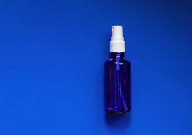 Mavi arka planda mavi bir şişe antiseptik sprey.