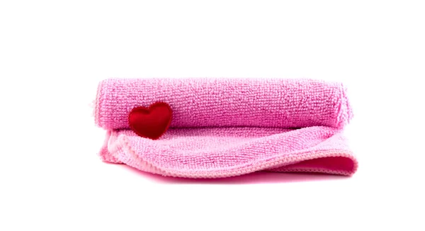Розовое полотенце и красное сердце закатились на белом фоне — стоковое фото